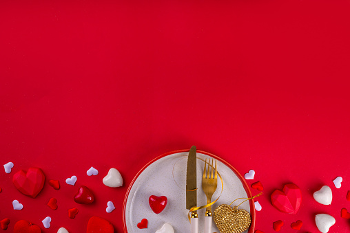 Valentine day  table setting background table setting for romantic dinner on red background, top view. Valentine's day celebration menu, greeting card or invitation background, Galentine day flat lay