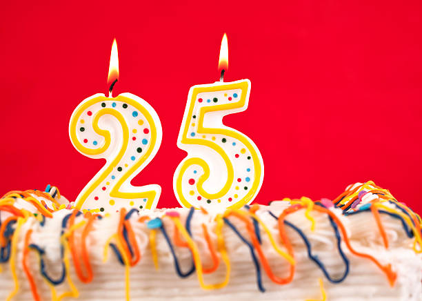 istock Decorated birthday cake with number 25 burning candles. Red background. 182462793