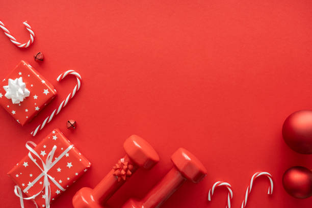 istock Gym workout dumbbells, Christmas gift boxes, ornaments. Exercise equipment as present idea. Sport gifts flat lay composition with copy space on red background. 1824628175
