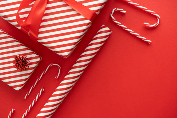 рулон оберточной бумаги с красными и белыми полосками, полосатый узор, рождественские подарочные коробки и леденцы. праздничная композици� - hard candy candy mint wrapped стоковые фото и изображения