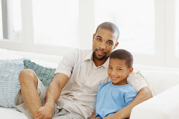 istock Father sitting with his son on couch 182463351