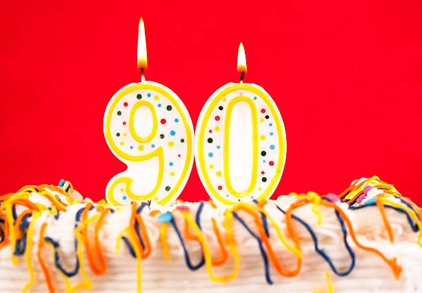 istock Decorated birthday cake with number 90 burning candles. Red background. 182464065