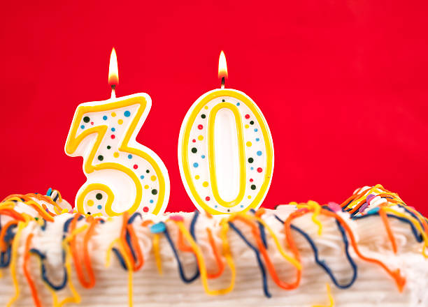 istock Decorated birthday cake with number 30 burning candles. Red background. 182464224