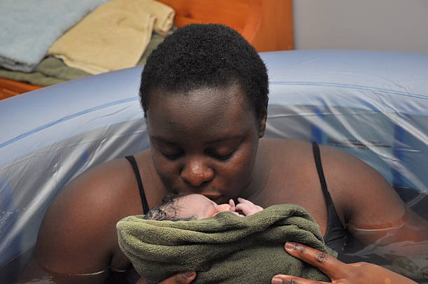 Baby-Day; water birth, mother kissing newborn stock photo