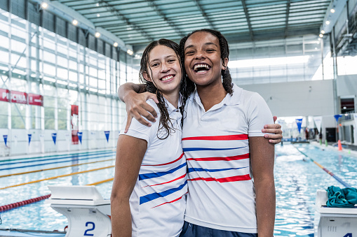 Portrait of teenage friends embracing at swimming school