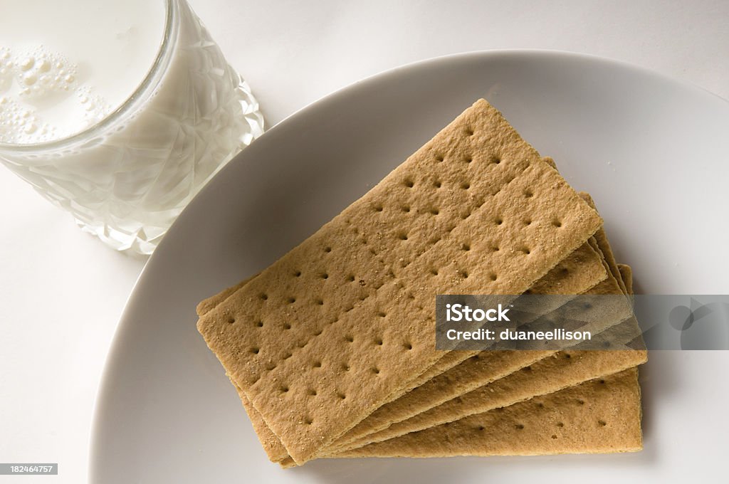 Graham Crackers with Milk A white plate of delicious stack graham crackers and a frosty iced cold glass of milk read to eat shot from above. Cracker - Snack Stock Photo