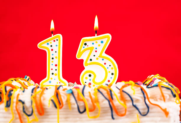 istock Decorated birthday cake. Number 13 burning candles. Red background. 182465713