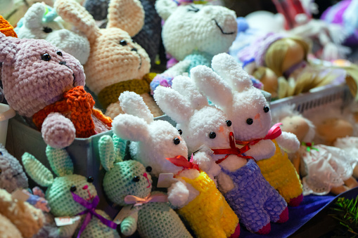 Colorful rabbits, handmade knitted toys lay on the counter in a gift shop