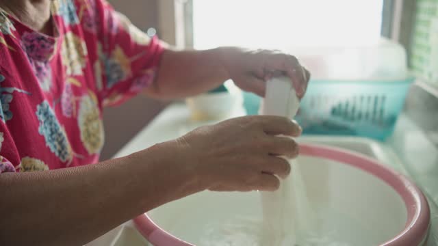 Elderly Woman’s Daily Life: Washing Clothes at Home.
