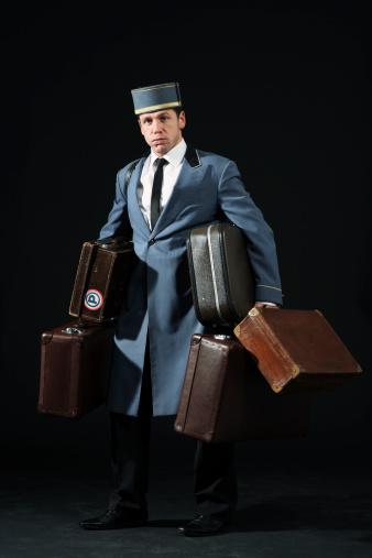 retro bellboy carrying a gig set of suitcases old traditional uniform