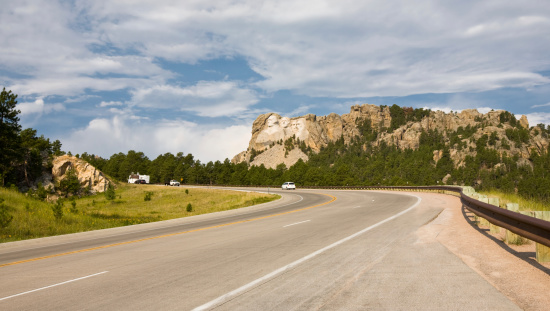First look at Mt. Rushmore National Monument- road with cars and an RV leading to the  famous monument in South Dakota