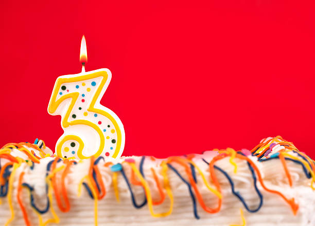 istock Decorated birthday cake with number 3 burning candle. Red background. 182468242