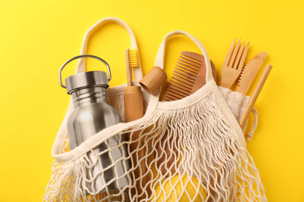 istock Fishnet bag with different items on yellow background, top view. Conscious consumption 1824683498