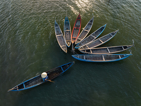 Drone view a woman is dragging and nailing wooden fishing boats, which made a flower shape on O Loan lagoon - Phu Yen province, central Vietnam