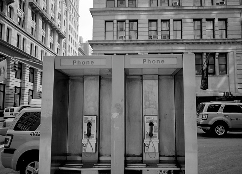 Lone phone booth stands in an open field covered with snow.