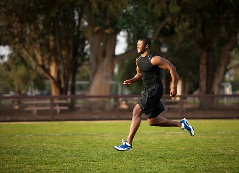 Action shot of a muscular college-aged african american male doing aerobic exercises (running) to keep fit and healthy.