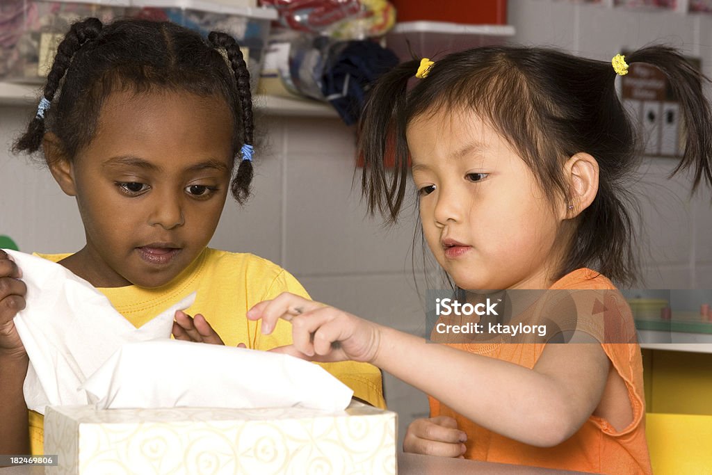 Preschoolers grabbing tissues Two preschool girls reaching for tissues Classroom Stock Photo