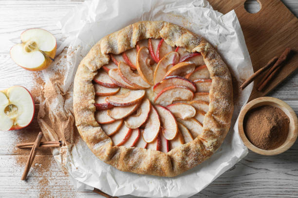 istock Delicious apple galette and cinnamon on white wooden table, flat lay 1824702255