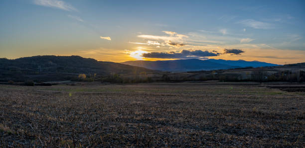 Sunset over the mountain. The sun's rays fall on the plowed fields and on the forest at the bottom of the mountain.