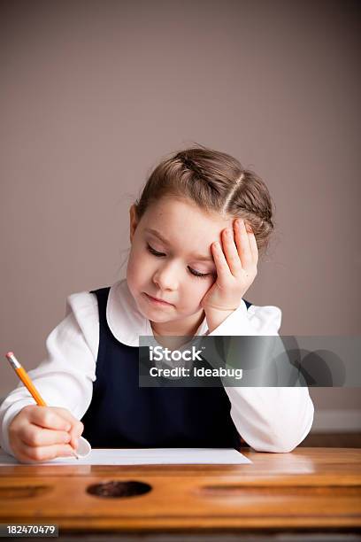 Photo libre de droit de Jeune Fille Étudiant À Lécole Assis À Un Bureau Décriture banque d'images et plus d'images libres de droit de Contemplation