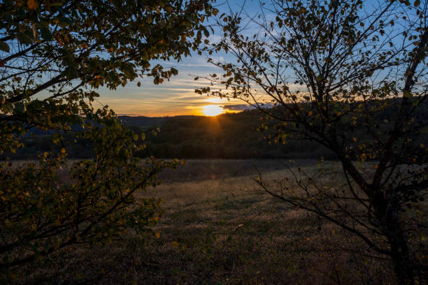 Sunset over the mountain. The sun's rays fall on the plowed fields and on the forest at the bottom of the mountain.
