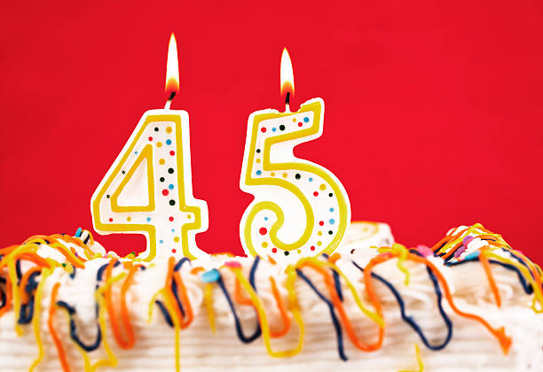 istock Decorated birthday cake with number 45 burning candles. Red background. 182470787