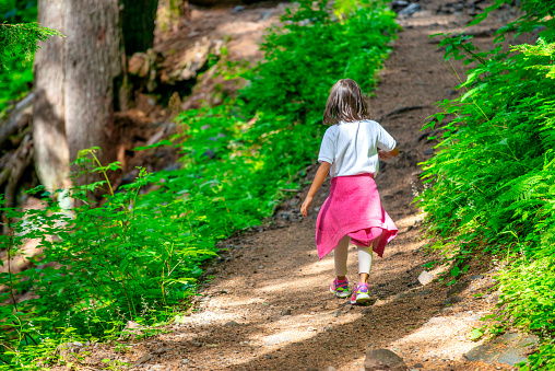 A shot of a young, unrecognisable girl walking through a muddy path in a forest in Northumberland, Northeastern England.