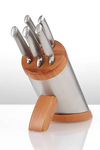 Modern knife block photographed with selective focus on a white reflective background.