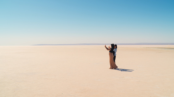 Two female multi-ethnic friend tourists are exploring and using their mobile smart phones to take photos and videos in Tuz Gölü Salt Lake in Anatolia region of Türkiye Turkey