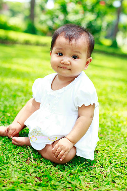 istock lovely baby sitting on the grass 182471294