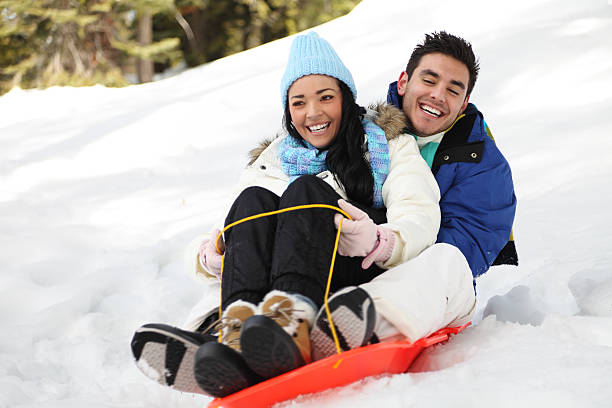 Couple Sledding In The Snow