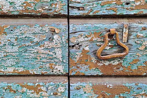 Old closed traditional wooden door with detached paint that need to be restored