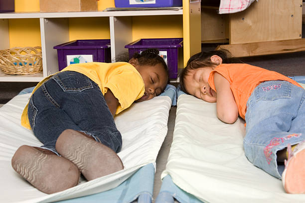 Two little girls asleep on cots at preschool