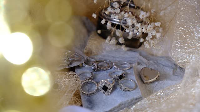 Close up of  golden beige   lace and fabric, jewelry silver rings  Luxury background with bokeh and glare
