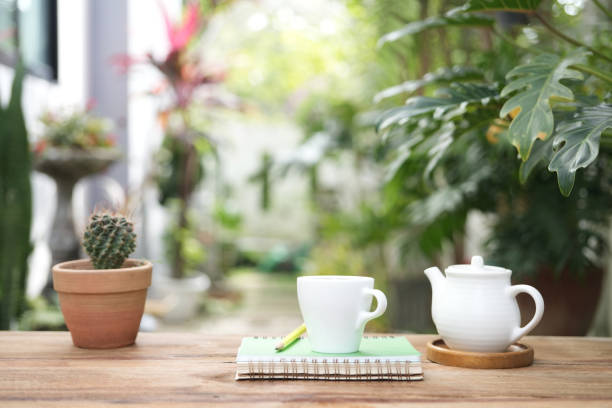 istock White tea kettle and white cup with notebook on wooden table outdoor garden view 1824732504