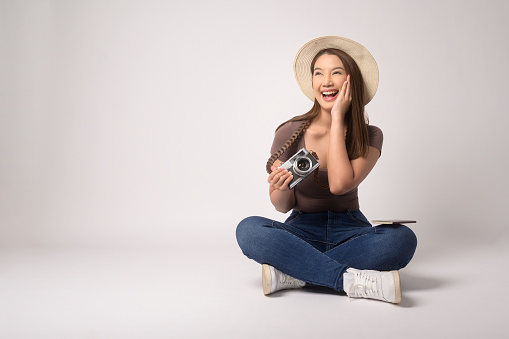 A Young happy asian tourist woman over white background studio, travel and holidays concept.