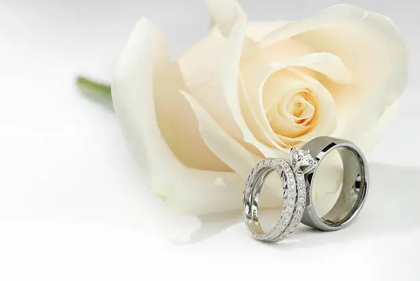 Photo of Wedding Rings and a White Rose