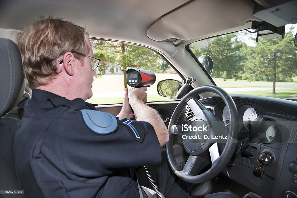 Police Radar A police officer sitting in his police cruiser using a radar gun on passing cars.More in the series. Speed Gun Stock Photo