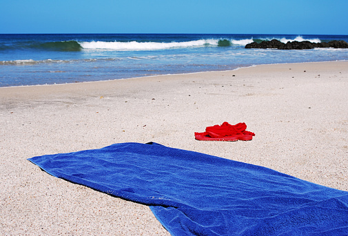 Flip Flop, sundress and towel laid on the beach.