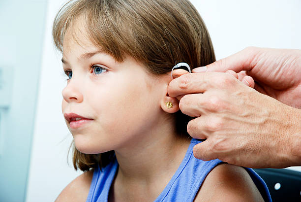 Doctor putting an earhorn in a child's ear Trying an ear horn. ear horn photos stock pictures, royalty-free photos & images