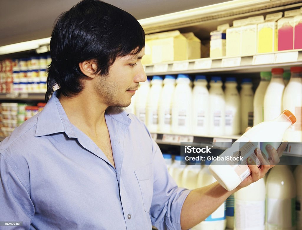 Młody człowiek trzyma Butelka mleka w supermarkecie - Zbiór zdjęć royalty-free (Handel detaliczny)