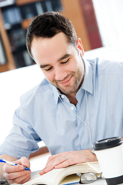 istock Man Sitting at a Desk Working With Coffee & Book 182477232
