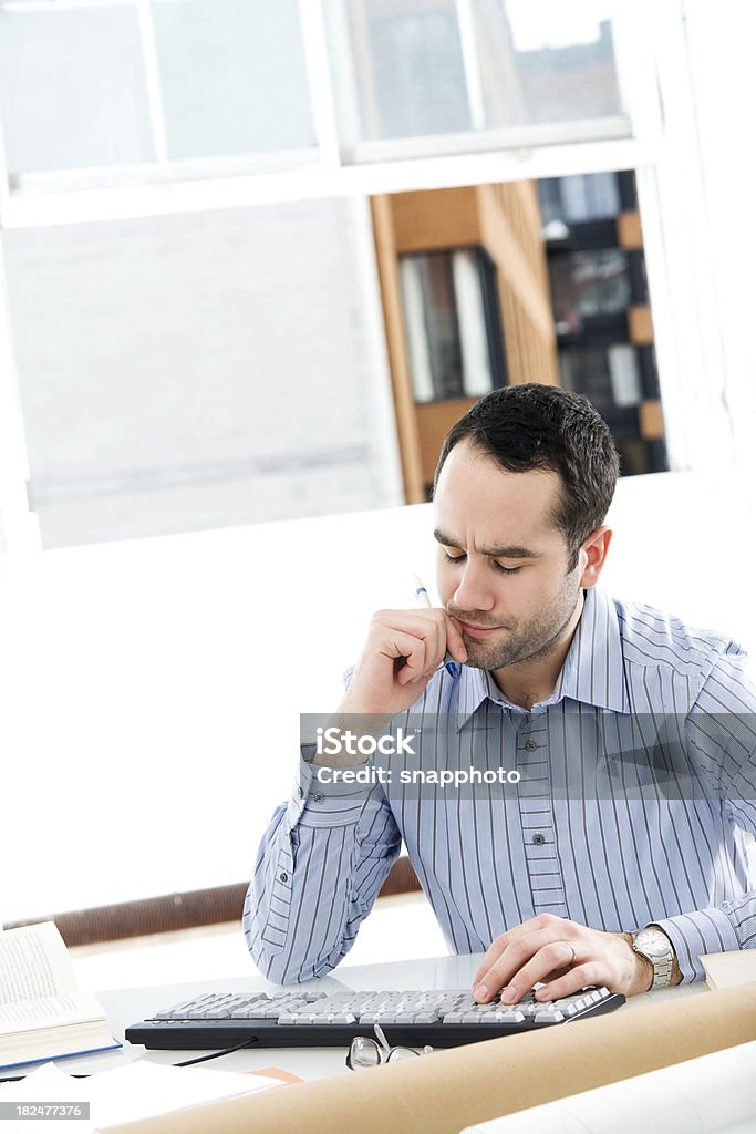 Hombre sentado en el escritorio de trabajo - Foto de stock de 25-29 años libre de derechos