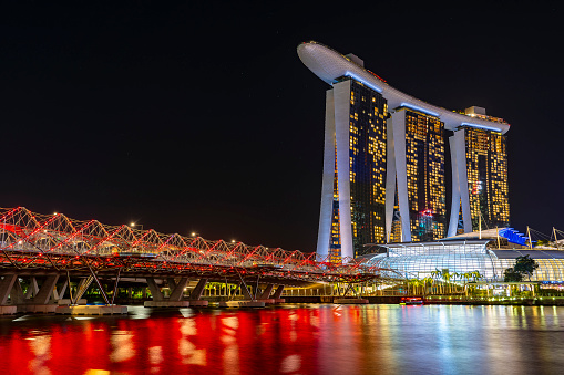 Singapore - Feb 25, 2020. Famous tourist destination - Marina Bay Sands , Shoppes mall, ArtScience museum and Helix bridge in Marina bay, Singapore, on sunny day. Must-see landmarks of city-state, clear blue sky, azure waters. Iconic futuristic architecture and symbols.