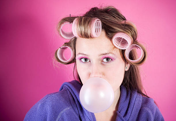 istock Young woman with curlers and bubble gum 182477785