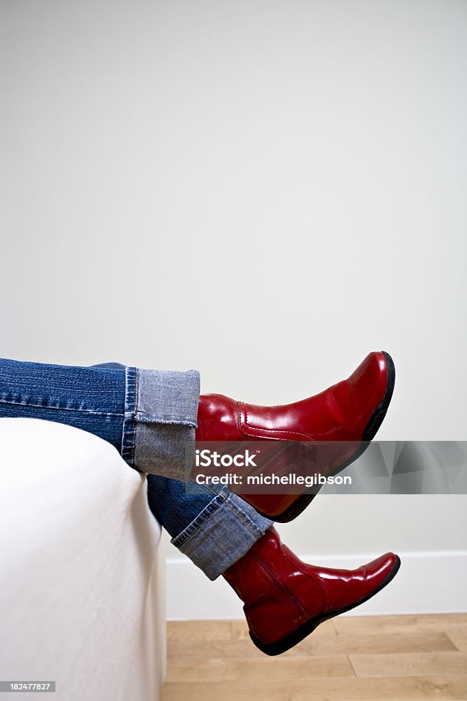 Une femme s'agiter jambes portant ourlets de jeans et chaussures rouges. - Photo de Canapé libre de droits