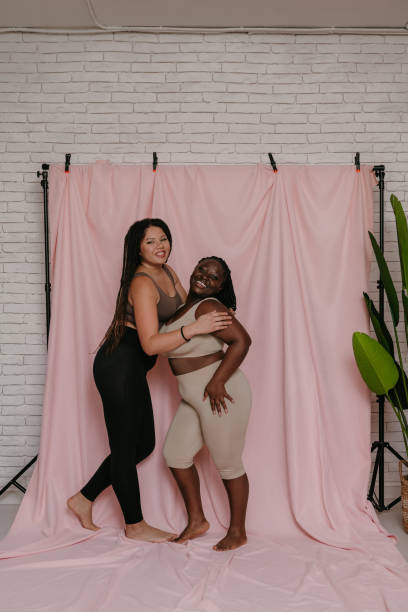 istock Two beautiful plus size African women in sportswear smiling while bonding on fabric background 1824780518