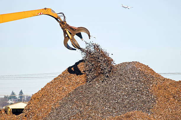 Crane releasing shredded metal onto pile of scrap at recycling plant