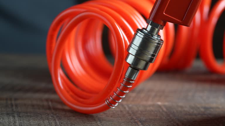 Worker connects orange air hose to air blow gun via hose coupling, close up