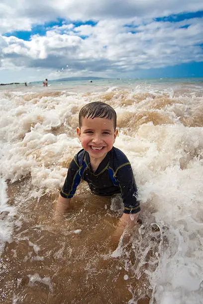 A young boy playing in the waves at a beach.